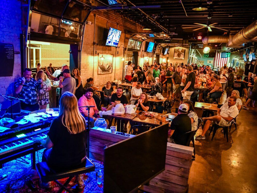 woman plays piano inside brewery filled with spectators